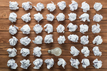 Ideological concept with wastepaper light bulb on wooden table