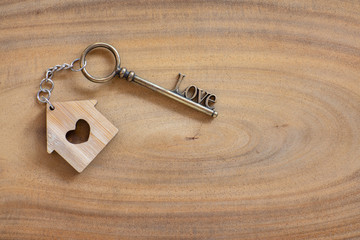 House key in heart shape with home keyring on old wood background