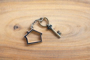 House key in heart shape with home keyring on old wood background