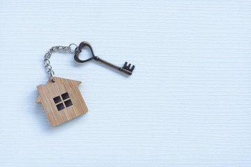 House key in heart shape with home keyring on old wood background