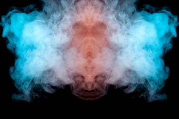 Obraz premium Mystical pattern of green, blue and pink colored smoke in the shape of a ghost's face with big eyes and an open mouth creating a feeling of fear on a black isolated background from a horror movie.