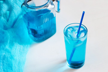 Glass with a blue cocktail with ice on a white background. © Elena