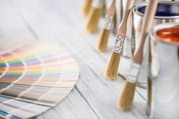 Paint cans brushes and color palette on table