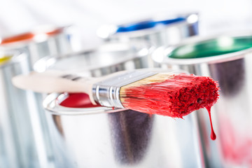 Close-up brush with red color lying on paint can.
