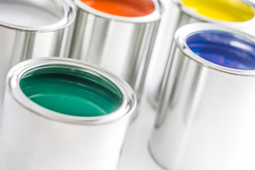 Full of multicolored paint cans on white table