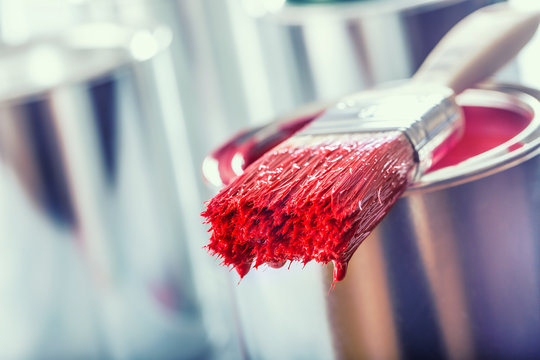 Close-up brush with red color lying on paint can.