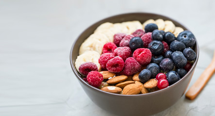 Healthy breakfast with acai bowl, raspberries, blueberries, almonds, bananans , healthy granola or muesli bowl with fresh berries