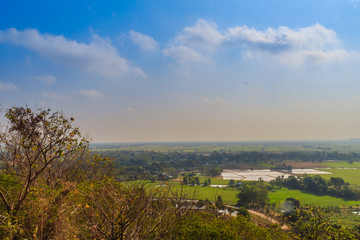 Aerial view from hilltop around with countryside green rice fields and blue sky background at Wat Khao Rup Chang or Temple of the Elephant Hill ,Phichit province, Thailand.