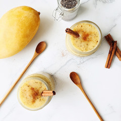 Mango yogurt smoothie with chia seeds and cinnamon on a marble background, top view