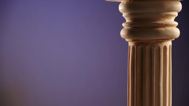 Single ancient greek column rotating slowly on color background, copy space text area