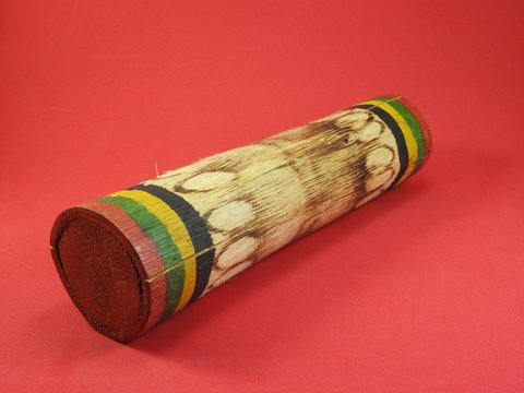 Close-up of a &ldquo;ganz&aacute;&rdquo;, a Brazilian rattle used as a percussion instrument, especially in samba music. It is handmade, colorful and made of bamboo. Pink background.