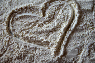 Heart shaped on flour on a white plate. Cooking with love, baking background.