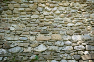 Old textured stone wall of large cobblestones.