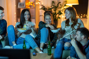 friendship, and leisure concept - happy friends with non-alcoholic drinks and snacks watching tv at...