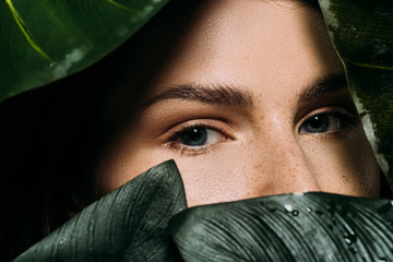 attractive woman with freckles posing with green palm leaves