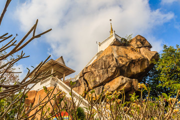 Stair way upward to the golden pagoda on the hill with blue sky background at Wat Khao Rup Chang or Temple of the Elephant Hill, one of the most famous attractions in Phichit province, Thailand.