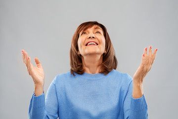 happiness and old people concept - portrait of smiling senior woman looking up over grey background