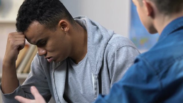 Teenager scolding his silent depressed friend, high school relationship problems
