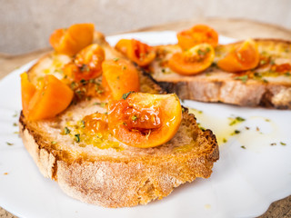 grilled bread bruschetta with Italian tomatoes, orange color, very good and long-lasting, seasoned with olive oil and oregano, for a healthy breakfast, close-up shot, on wooden floor outdoors