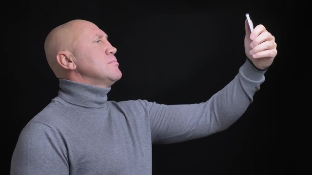 Closeup portrait of adult caucasian man taking selfies on the phone with background isolated on black