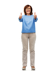 gesture and old people concept - smiling senior woman in glasses showing thumbs up over white...