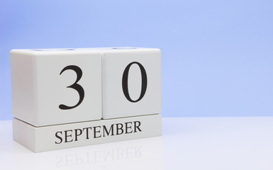 September 30st. Day 30 of month, daily calendar on white table with reflection, with light blue background. Autumn time, empty space for text