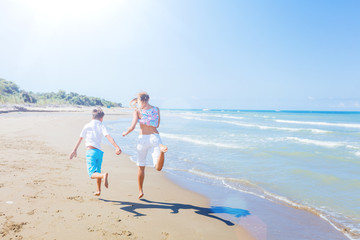 Back view of Happy kids running on tropical beach