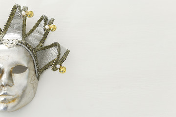 silver with gold elegant traditional venetian mask over white wooden background