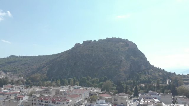 Panning from left to right above the city of Nafplio in Greece. Showing the urban setting while the hill in which the Palamidi Castle stands in the background. Sunny weather. Flat profile but also ava