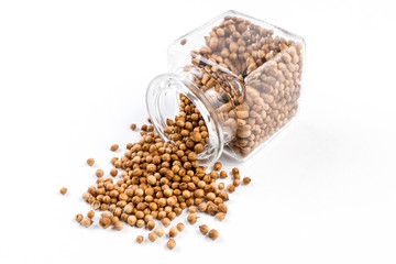 coriander seeds in a glass jar isolated on white background