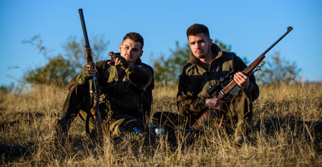 Hunters with rifles relaxing in nature environment. Hunter friend enjoy leisure in field. Hunting with friends hobby leisure. Hunters gamekeepers relaxing. Rest for real men concept. Discussing catch