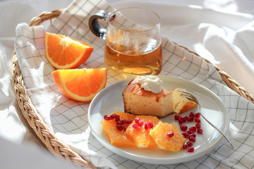 Morning scene with a piece of cake and some slices of orange with tea on a tray