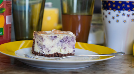 Piece of blueberry pie on a plate, glasses in the background