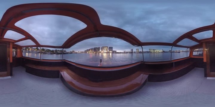 360 VR Video. Timelapse shot of boat traveling on Amsterdam canals at night. Touristic water trip to observe the capital of Netherlands