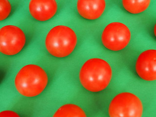 several bright red cherry tomatoes on a green background