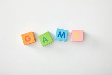 top view of game lettering made of multicolored cubes on grey background