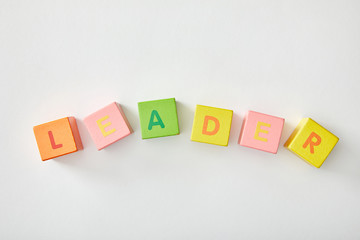 top view of leader lettering made of multicolored cubes on white background