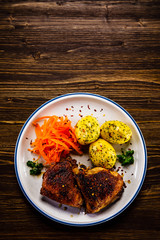 Grilled thighs with boiled potatoes and vegetable salad on wooden table