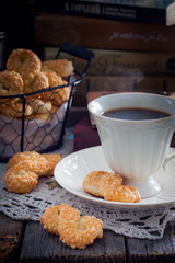 Cookies with cheese in the form of eight on a wooden table with a cup of coffee on the background of books, selective focus