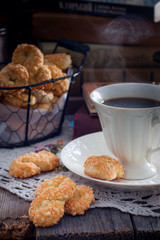 Cookies with cheese in the form of eight on a wooden table with a cup of coffee on the background of books, selective focus