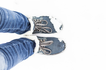 Top view of the feet in the blue boots and legs in the jeans on the white snow. Copy space. Place...