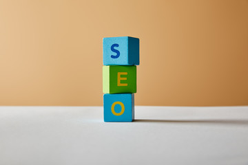 vertical seo lettering made of multicolored blocks on white table and beige background