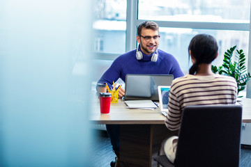 Positive delighted male person looking at his colleague