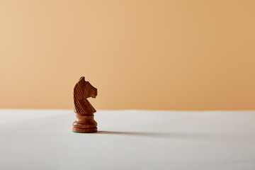 wooden knight piece on white table and beige background