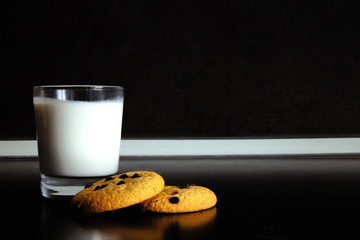 Good morning. Breakfast Cookies and a glass of milk. yogurt. Black background. Minimal black and white