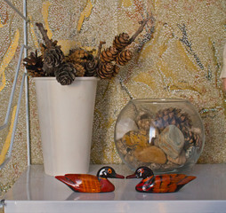 Two wooden ducks, a vase with cones, a glass with stones, still life