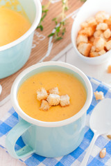 Pumpkin soup in a blue enameled mug, selective focus