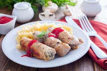 Small pork rolls - pork fingers, with mushrooms on a white plate with pasta and ketchup, horizontal