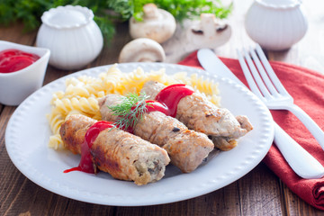 Small pork rolls - pork fingers, with mushrooms on a white plate with pasta and ketchup, horizontal