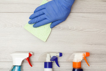Hand in rubber glove holding microfiber napkin with water sprayer.